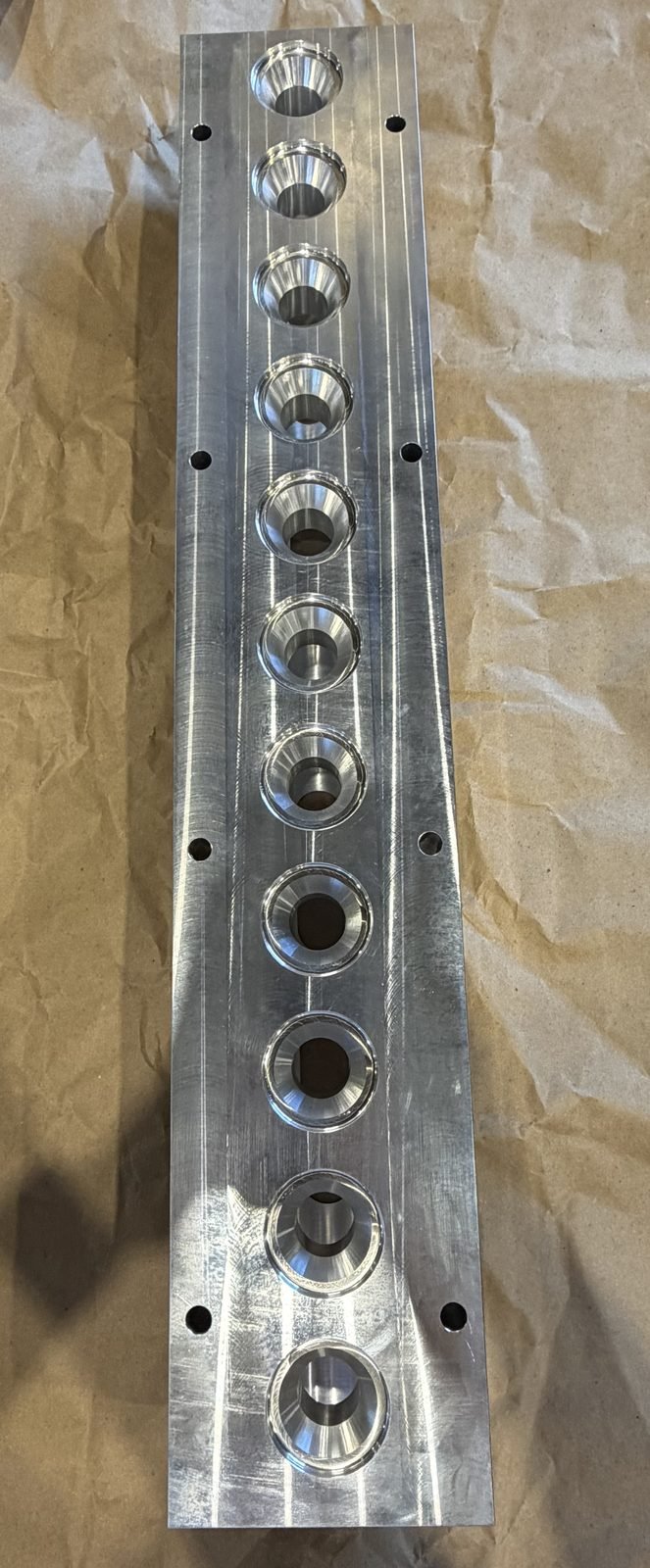 CNC-machined aluminum manifold block with a row of tapered bored ports