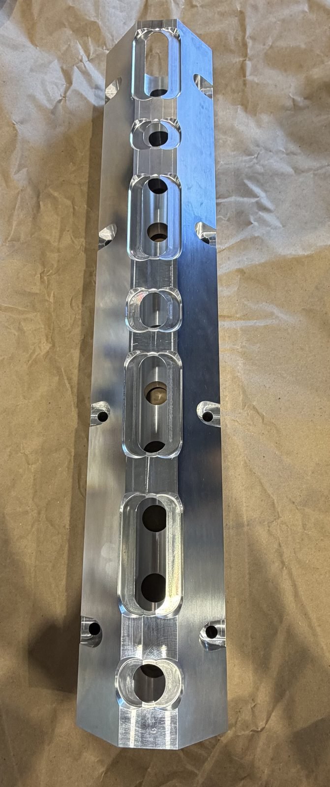 CNC-milled aluminum plate with a row of oblong pocket cutouts