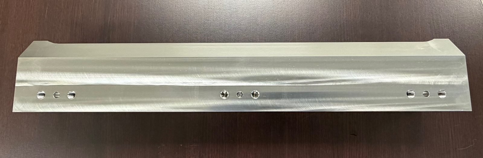 Machined aluminum bar with a row of threaded mounting holes