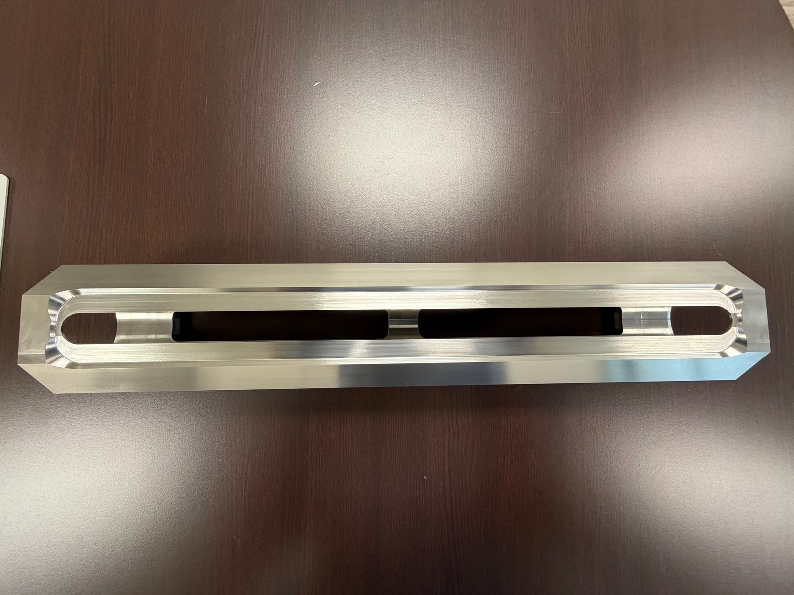 Machined aluminum fixture bar with elongated slot cutout, top view